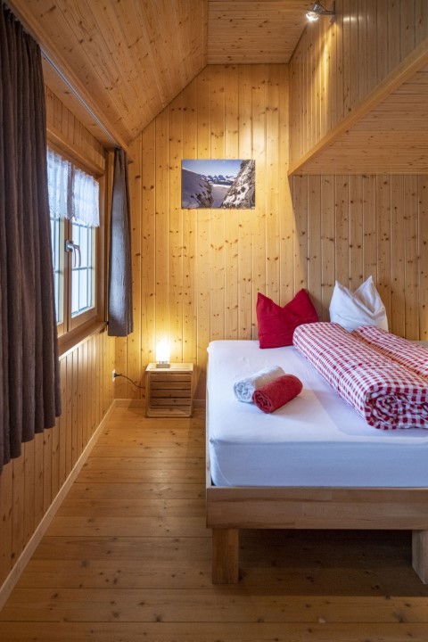 Bild eines Gästezimmers. Holzverkleideter Raum mit Bett.